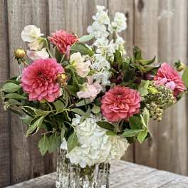 Pink and white flowers arranged in a clear glass vase