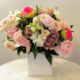 Pink and peach mixed bouquet in a white square vase