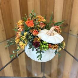 White pumpkin filled with orange flowers and greenery