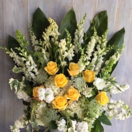 Yellow roses and white flowers arranged in a white vase
