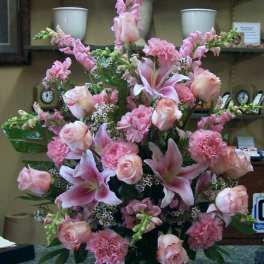 Pink floral arrangement with roses, lilies, and carnations in a white vase