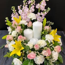 Floral candle arrangement with pink and white flowers and yellow lilies