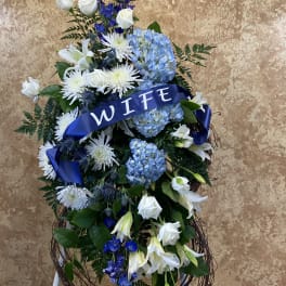 Large blue and white floral standing spray with a ribbon reading WIFE