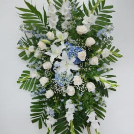 Standing floral spray with white lilies, roses, and blue accents