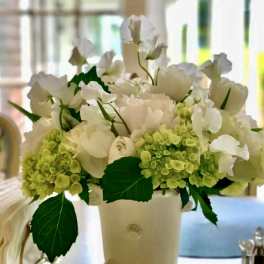 White flowers and pale green hydrangeas in a cream vase