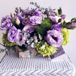 Purple lisianthus and green hydrangeas arranged in a low basket