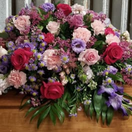 Large casket spray with pink, purple, and red flowers