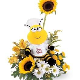 Bee plush in a floral arrangement with sunflowers and white daisies
