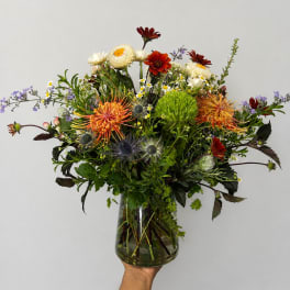 Mixed bouquet in a clear glass vase with orange, white, and red blooms
