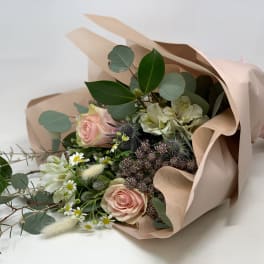 Bouquet of pink roses and white flowers wrapped in blush paper