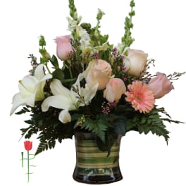Mixed bouquet of roses, lilies, and gerbera daisies in a glass vase
