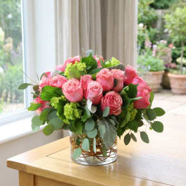Pink roses arranged in a clear glass vase with green foliage