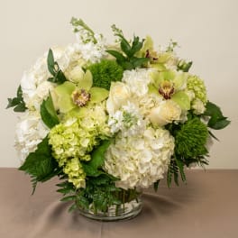 White and pale green floral arrangement in a clear glass vase