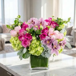 Pink roses and orchids arranged in a clear glass vase