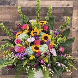 Large mixed bouquet with sunflowers, pink roses, lilies, and hydrangeas in a white vase