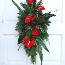 Red anthuriums and evergreen foliage arranged on a door wreath.