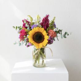 Sunflower bouquet in a glass jar vase with colorful mixed flowers
