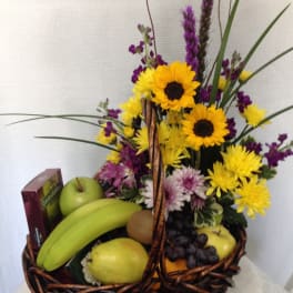 Fruit basket with sunflowers and purple flowers in a wicker basket