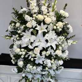 Large white floral standing spray with lilies and roses on an easel