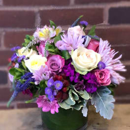 Mixed bouquet of roses and purple flowers in a green vase