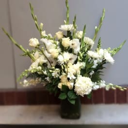 White floral sympathy arrangement in a dark vase