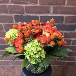 Bouquet of orange roses and green hydrangeas in a glass vase