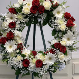 Circular wreath of red and white roses with white daisies on an easel
