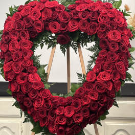 Heart-shaped wreath of red roses on a wooden easel
