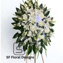 Tall white standing spray with lilies and other white flowers on a wooden easel