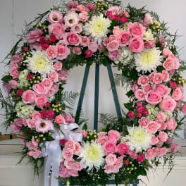 Large pink and white floral wreath on an easel with a white ribbon