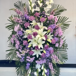 Standing floral spray with purple roses, white lilies, and lavender flowers