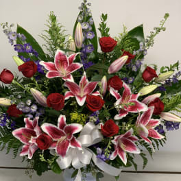 Large bouquet of pink lilies, red roses, and purple flowers in a white vase