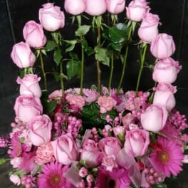 Pink roses arranged in a heart shape with pink daisies at the base