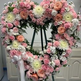 Heart-shaped floral wreath with pink and white flowers on an easel