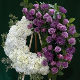 Floral wreath with white hydrangeas, purple roses, and purple mums on an easel