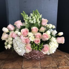 Pink roses and white flowers arranged in a woven basket