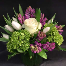 White rose and purple flowers in a glass vase