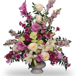 Tall pink, white, and green flower arrangement with lilies and roses in a white pedestal vase