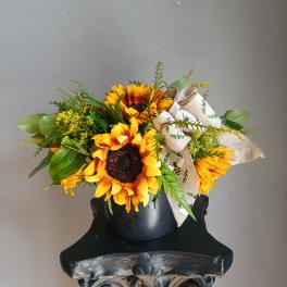 Sunflower arrangement in a black vase with a decorative ribbon