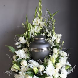 White floral funeral urn arrangement with roses, lilies, and chrysanthemums