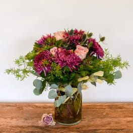 Purple and pink bouquet in a glass vase with eucalyptus