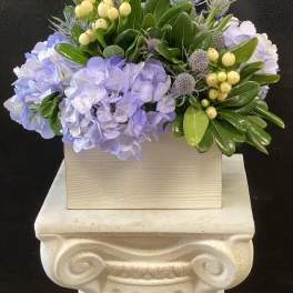 Lavender hydrangeas with yellow berries in a wooden box