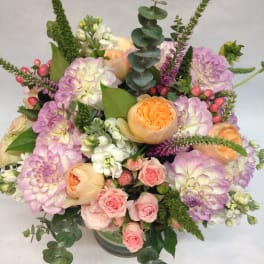 Pastel bouquet of roses, dahlias, and white blooms in a glass vase