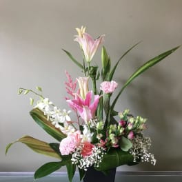 Pink and white floral arrangement in a black vase with tall lilies