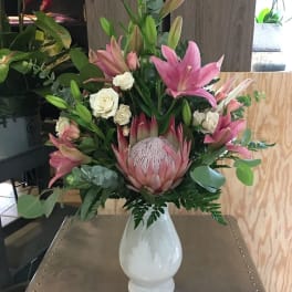Pink lilies and white roses arranged in a white vase