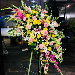 Large standing floral spray with pink, yellow, and white blooms