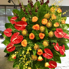 Large tropical floral standing arrangement with red anthuriums and orange roses