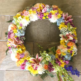 Circular floral wreath with mixed pink, yellow, blue, and orange blooms