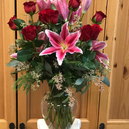 Bouquet of red roses and pink lilies in a clear glass vase