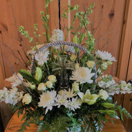 White floral arrangement with a glass cross in a basket